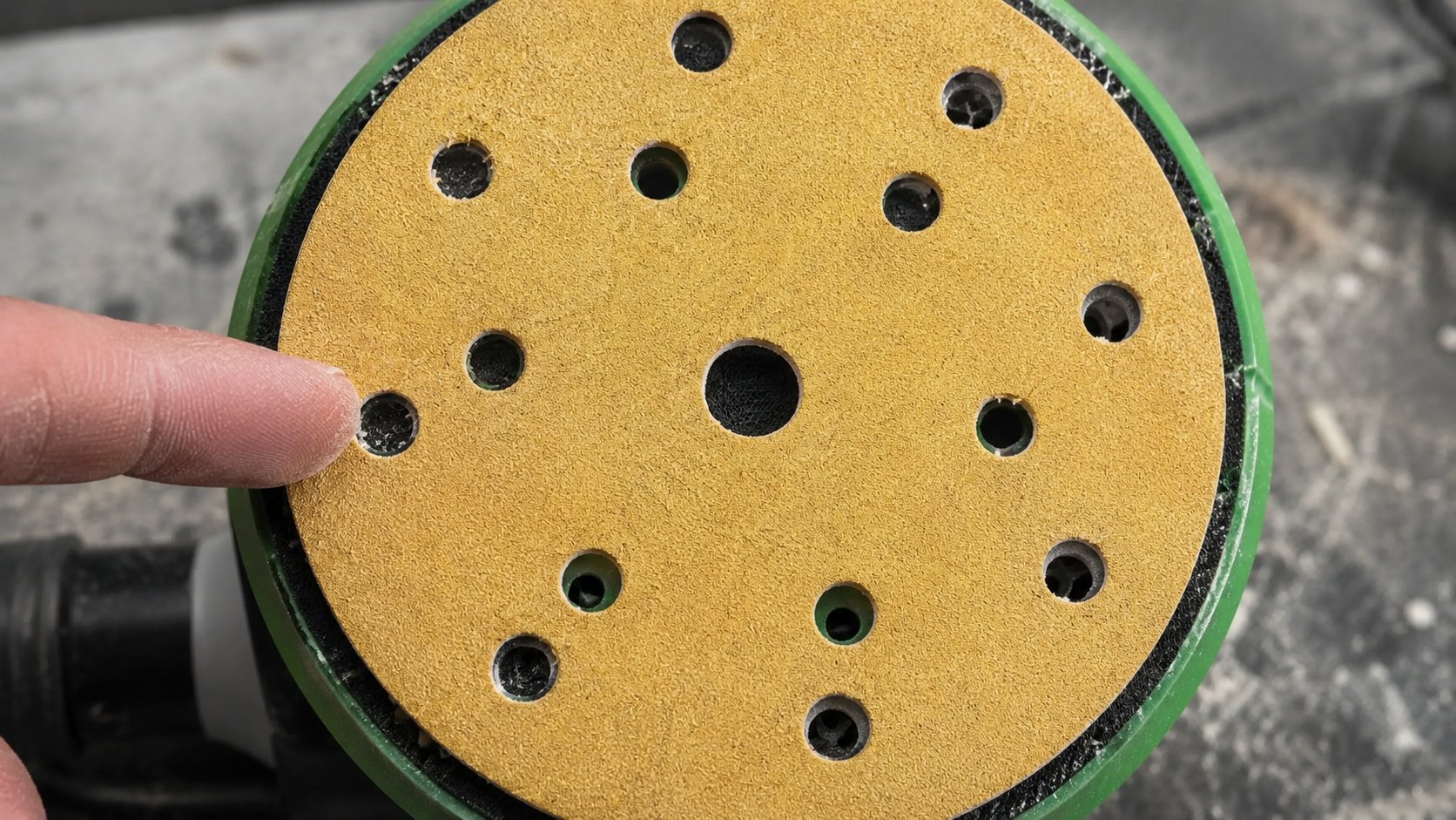 Misaligned sanding disc holes blocking dust extraction on a DA backing pad.