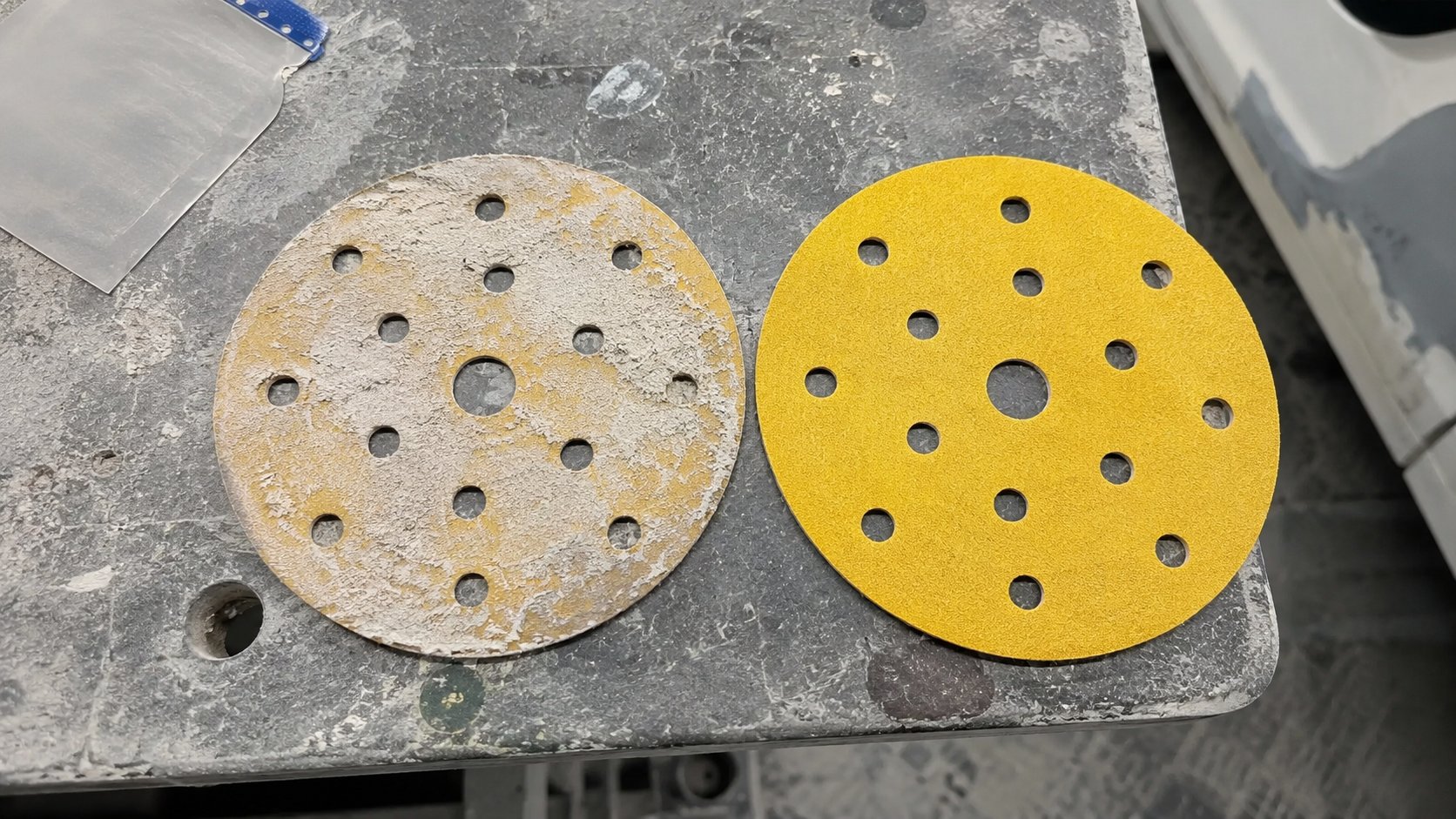 Clogged sanding disc compared with fresh abrasive disc for automotive prep